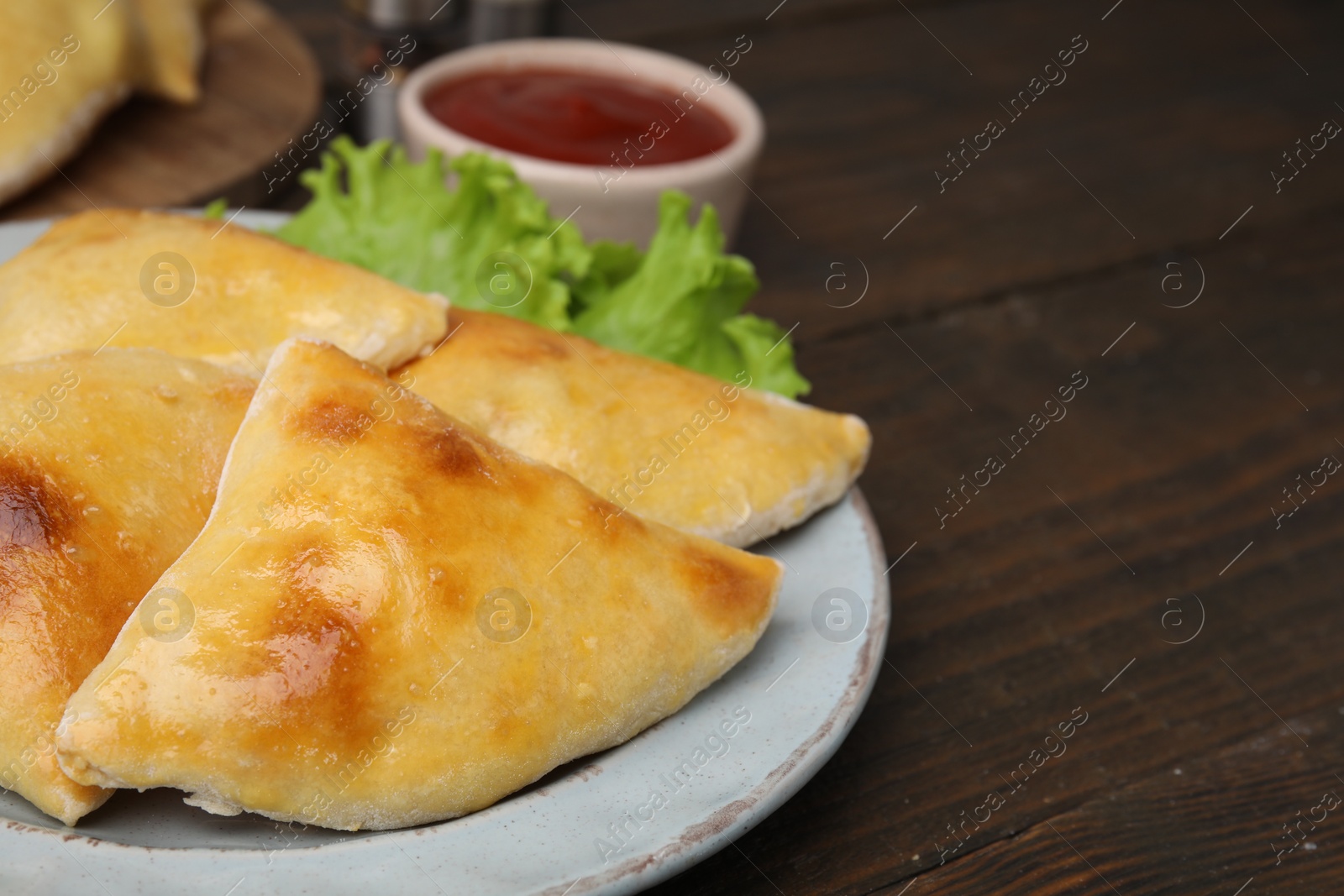 Photo of Delicious samosas and lettuce on wooden table, closeup. Space for text