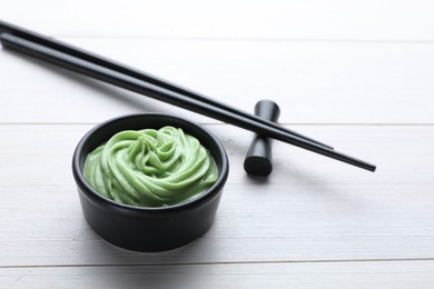 Photo of Bowl with swirl of wasabi paste and chopsticks on white wooden table