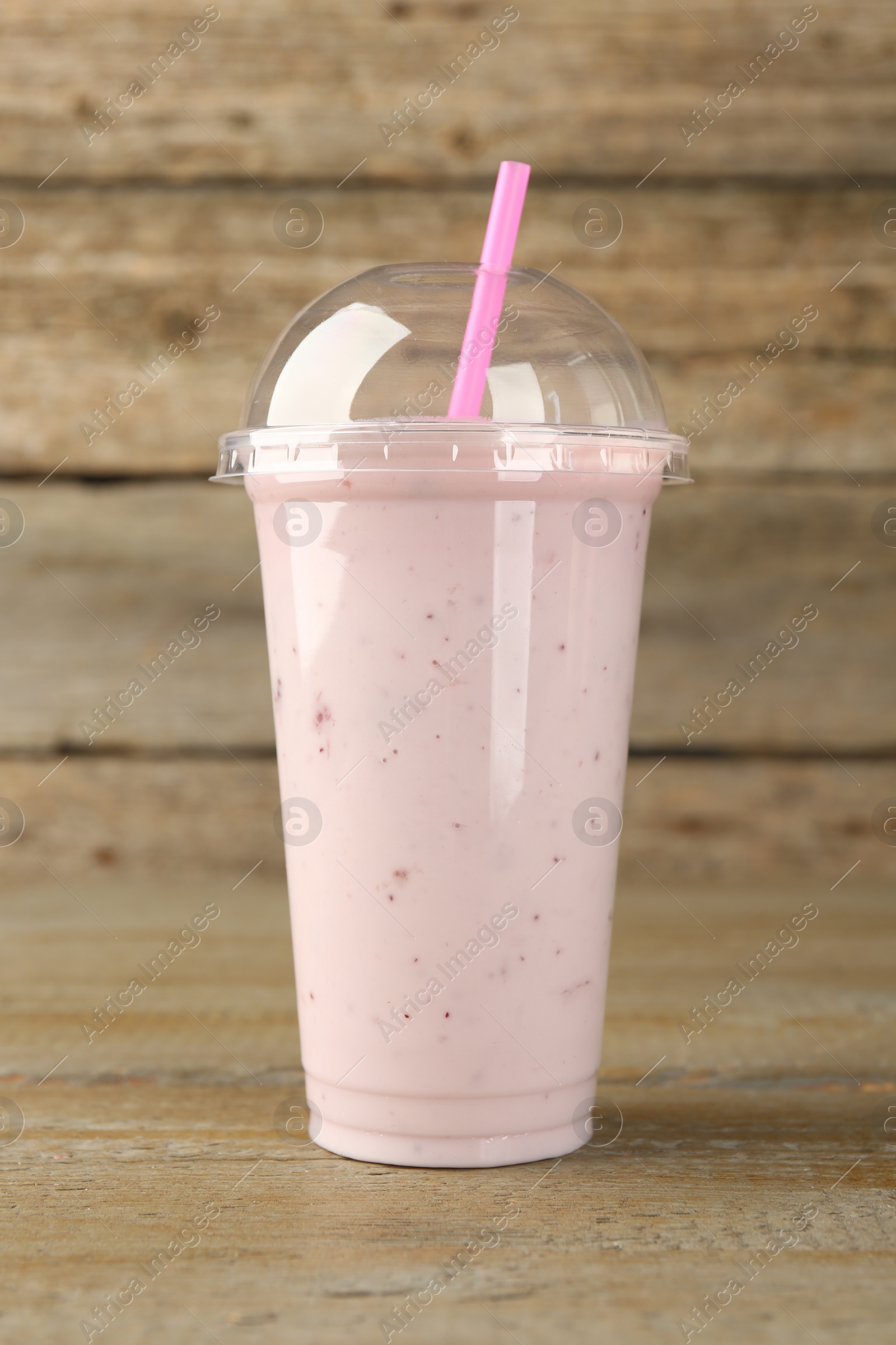 Photo of Plastic cup of tasty smoothie on wooden table