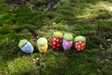 Photo of Colorful painted acorns with polka dot pattern on green moss outdoors