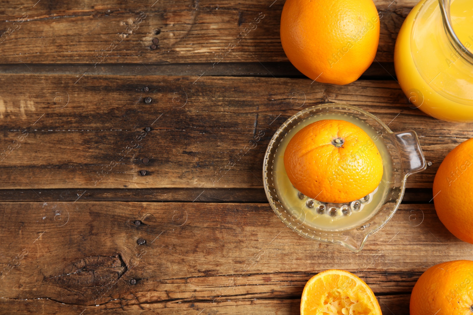 Photo of Fresh ripe oranges, squeezer and juice on wooden table, flat lay. Space for text