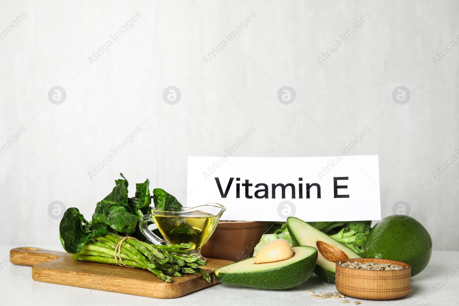 Photo of Card with phrase Vitamin E and different products on white background