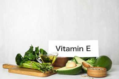 Card with phrase Vitamin E and different products on white background