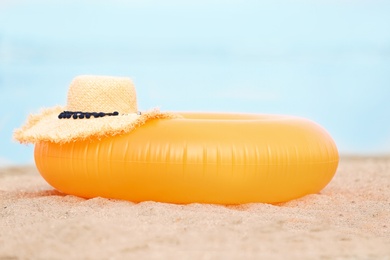 Photo of Colorful inflatable ring and hat on sand. Beach object