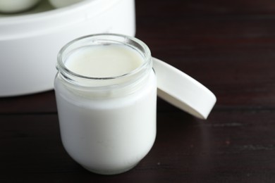 Photo of Glass jar with tasty yogurt on wooden table, closeup