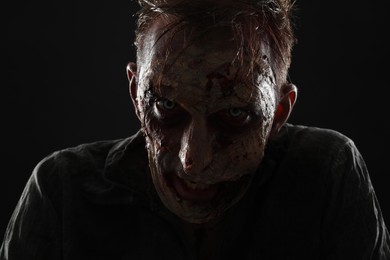 Photo of Scary zombie on dark background, closeup. Halloween monster