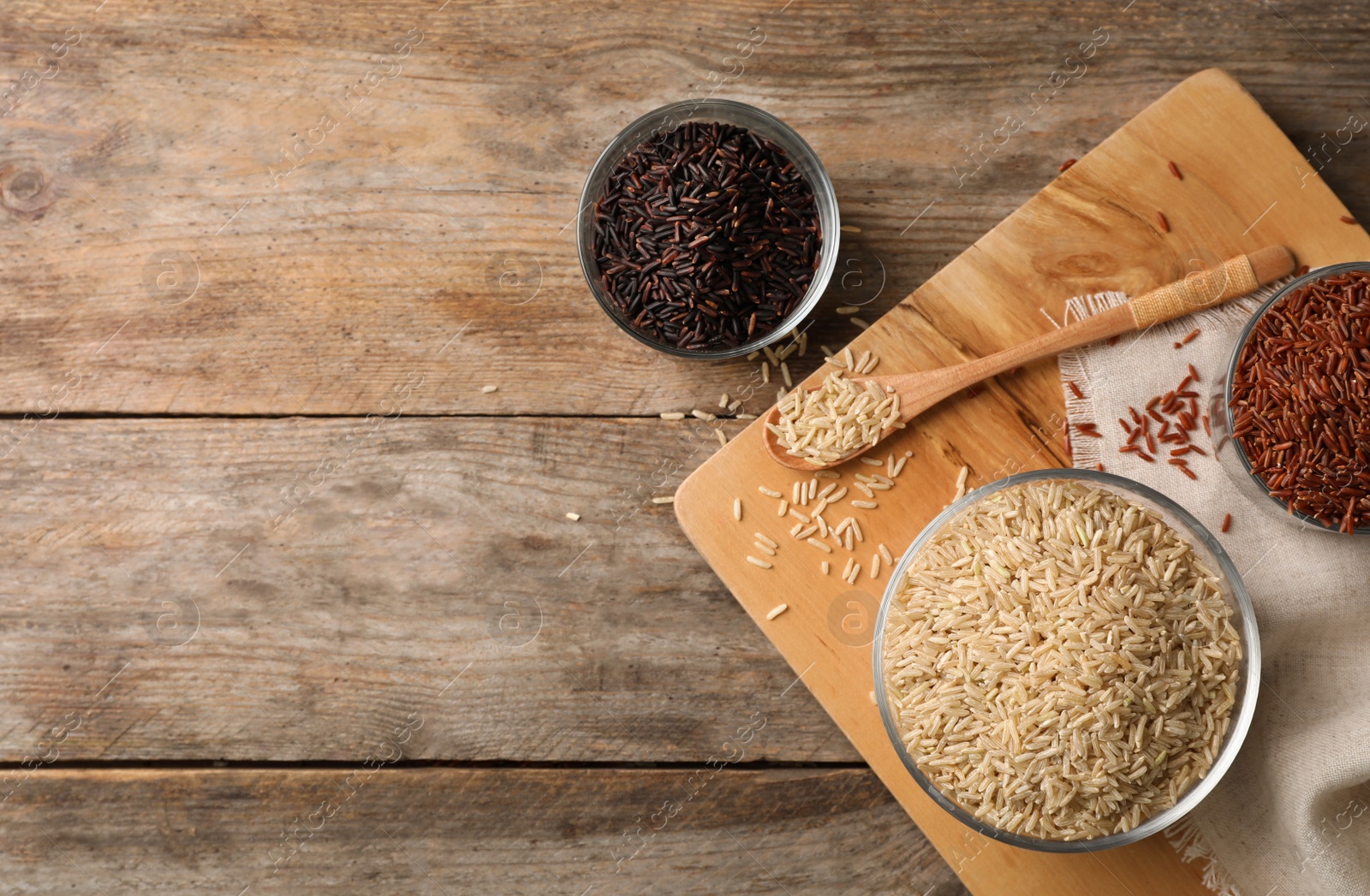 Photo of Flat lay composition with brown rice varieties on wooden table. Space for text