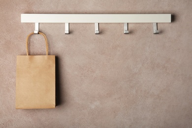 Photo of Rack with paper shopping bag on color wall