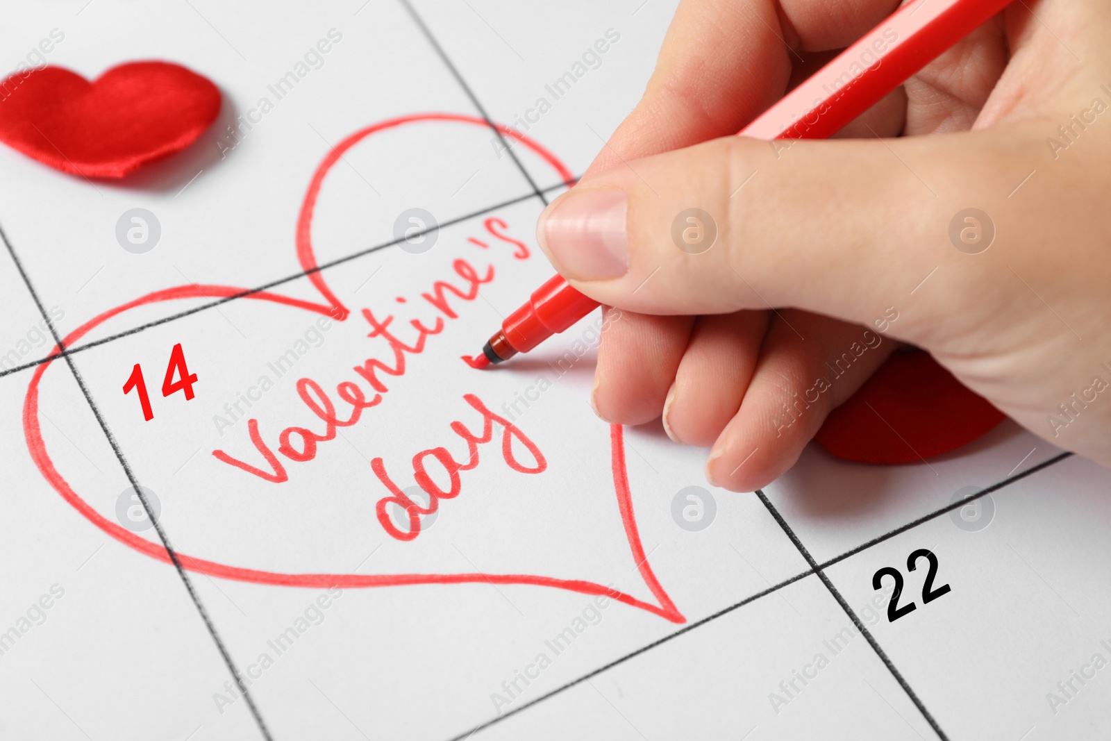 Photo of Woman marking Valentine's day with red marker on calendar sheet, closeup