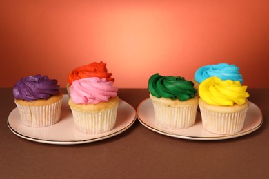 Delicious cupcakes with bright cream on color background