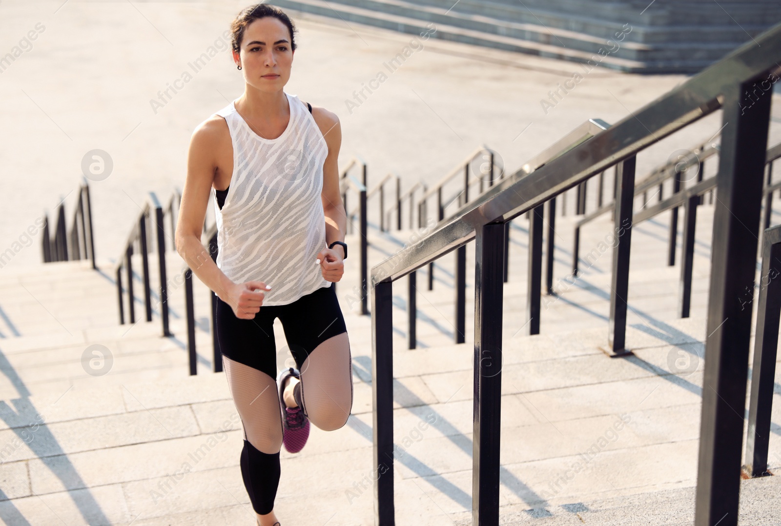 Photo of Sporty young woman running upstairs on sunny day