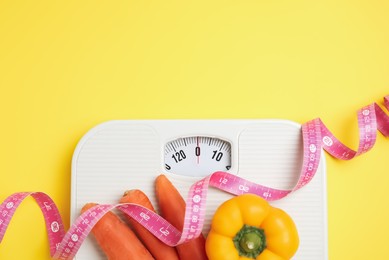 Photo of Flat lay composition with scales and vegetables on yellow background, space for text