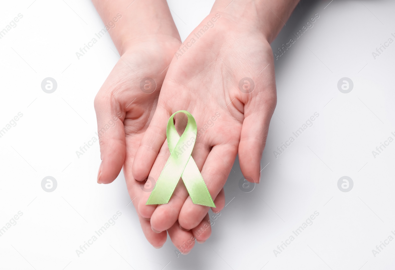 Photo of World Mental Health Day. Woman holding green ribbon on white background, top view