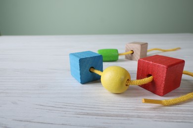 Photo of Wooden lacing toy on light table, closeup and space for text. Motor skills development