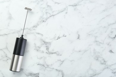 Photo of Black milk frother wand on white marble table, top view. Space for text