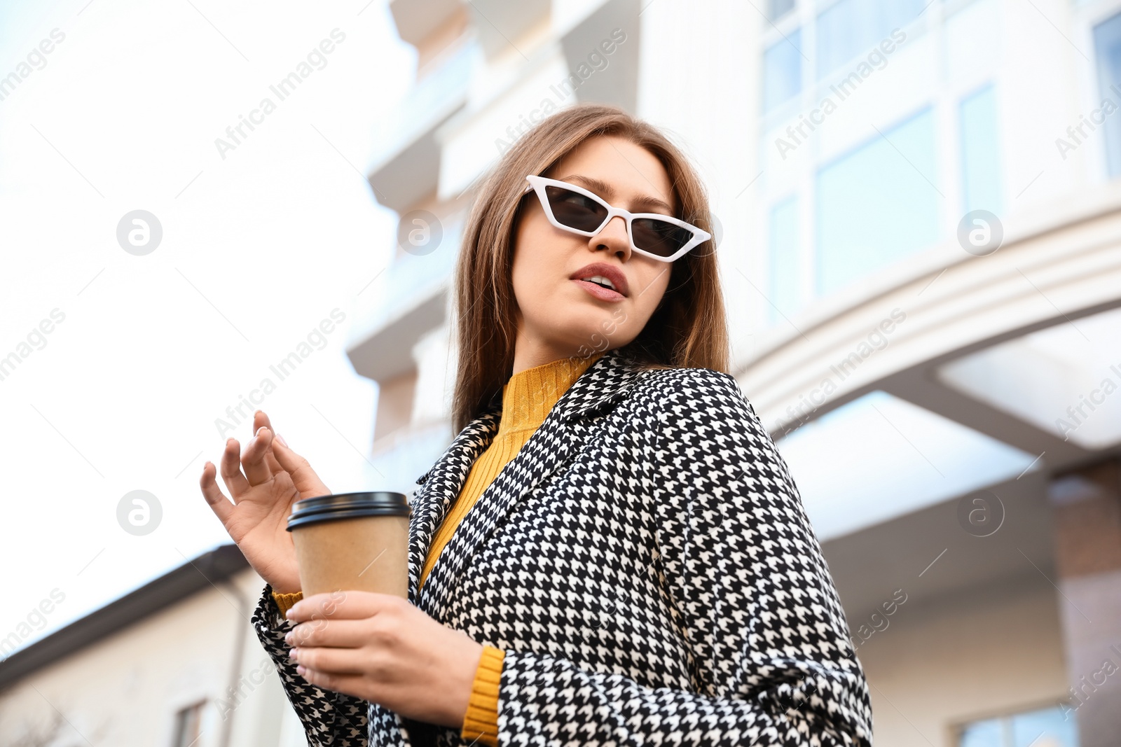 Photo of Young woman with cup of coffee on city street in morning