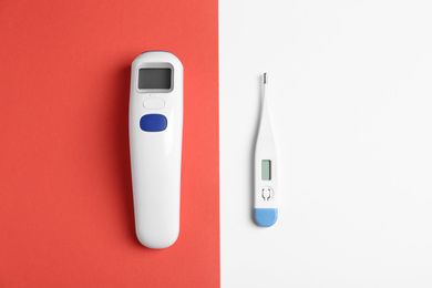 Photo of Non-contact infrared and digital thermometers on color background, flat lay