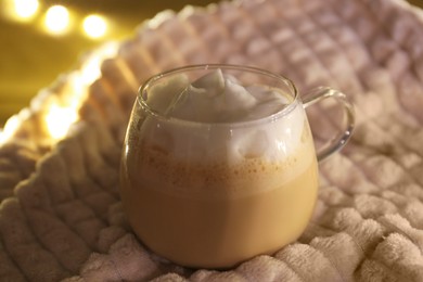 Glass cup of delicious hot cocoa on light blanket