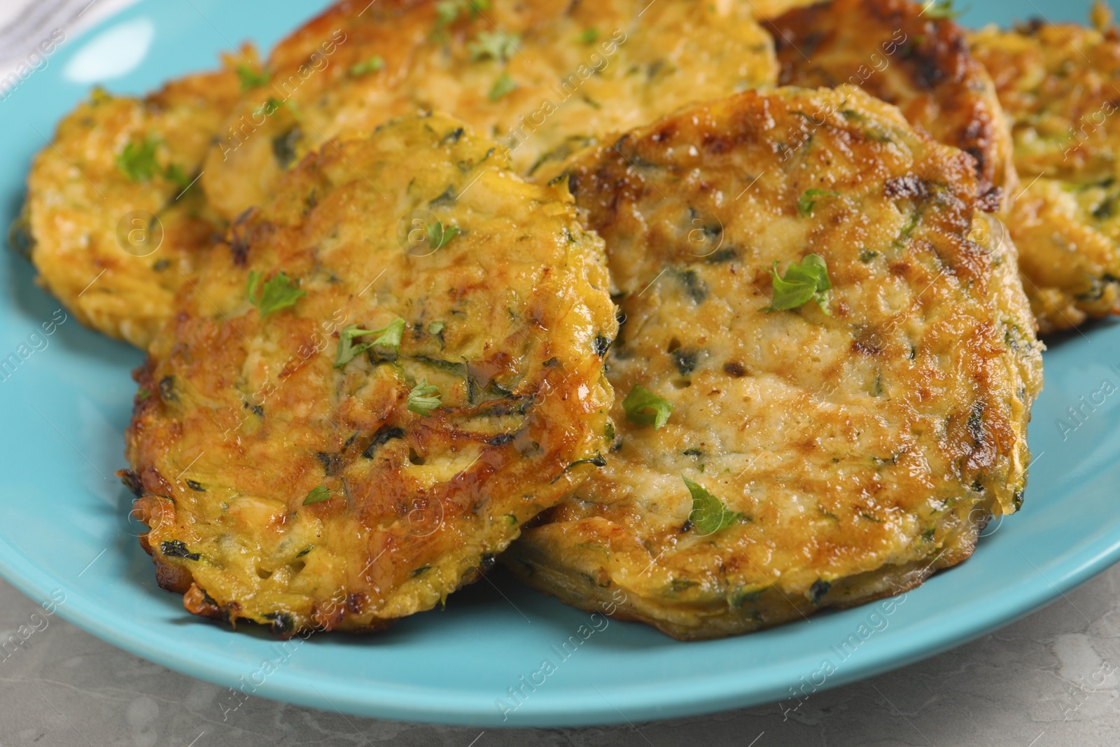 Photo of Delicious zucchini pancakes on grey table, closeup