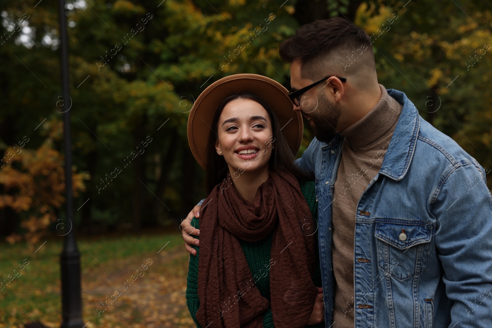 Photo of Romantic young couple spending time together in autumn park, space for text