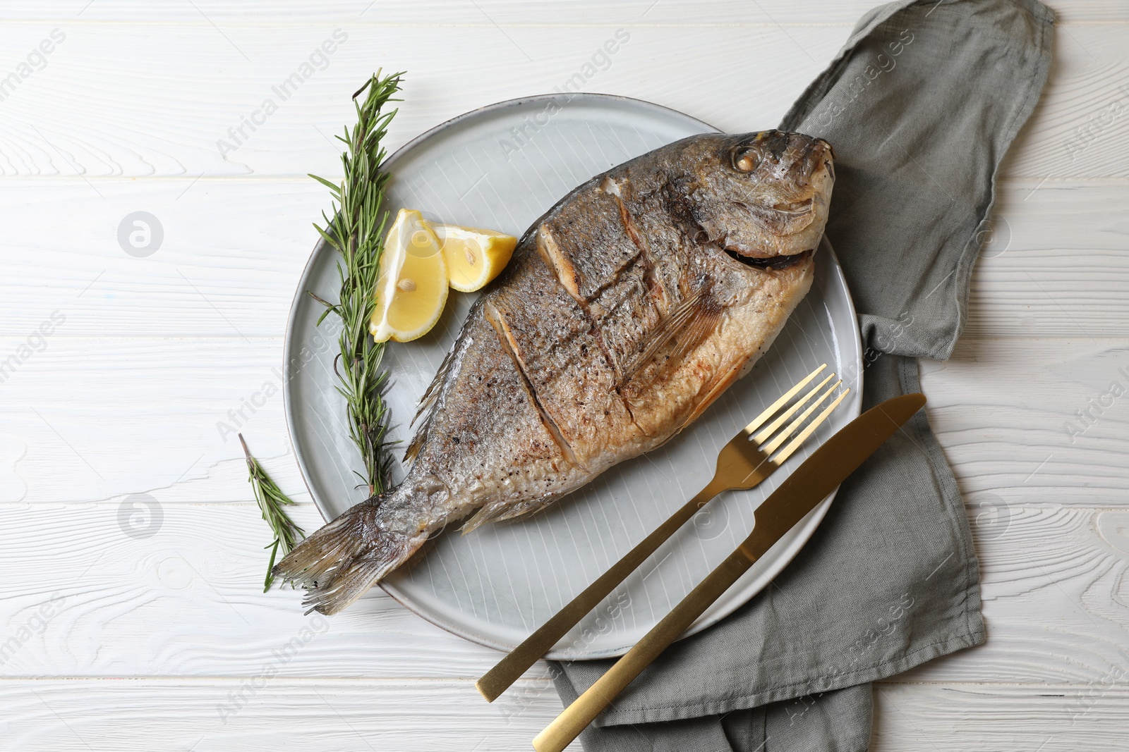 Photo of Delicious baked fish served with rosemary and lemon on white wooden table, top view. Seafood