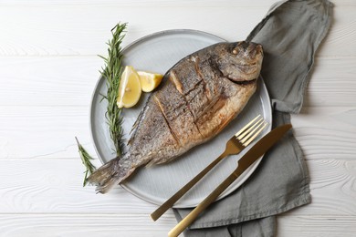 Photo of Delicious baked fish served with rosemary and lemon on white wooden table, top view. Seafood