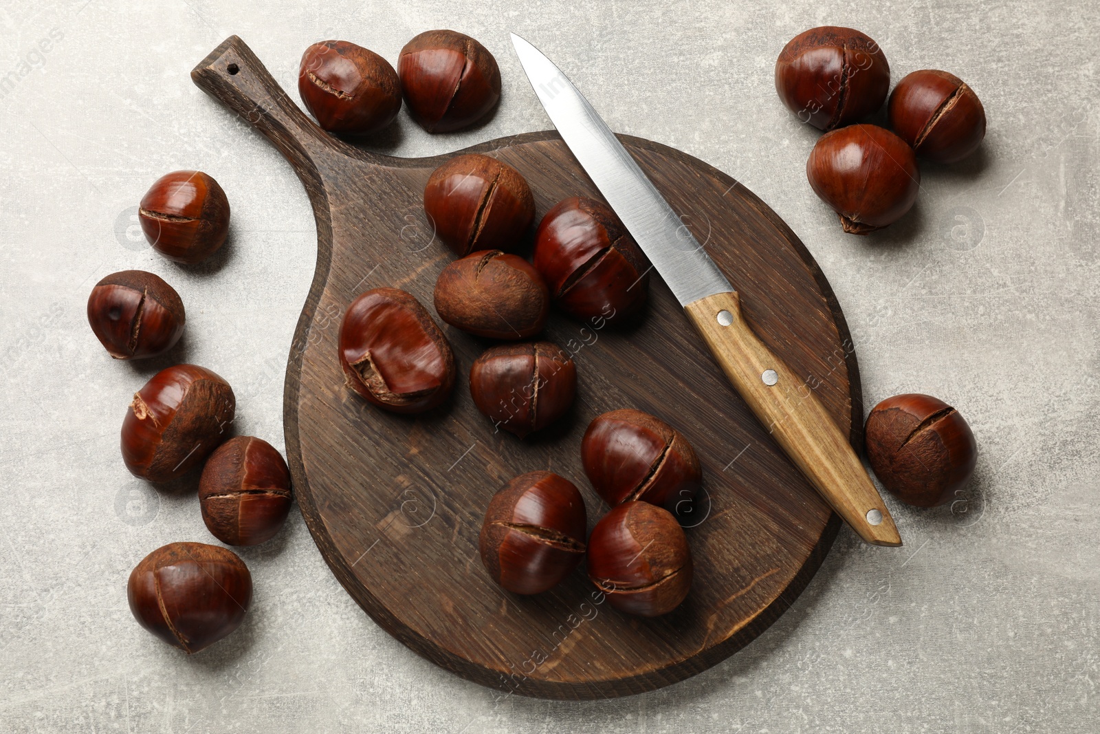Photo of Fresh edible sweet chestnuts and knife on grey table, flat lay