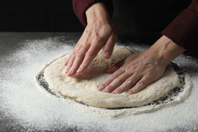 Photo of Woman kneading pizza dough at table, closeup