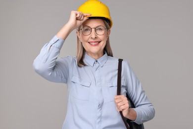 Photo of Architect in hard hat with tube on grey background