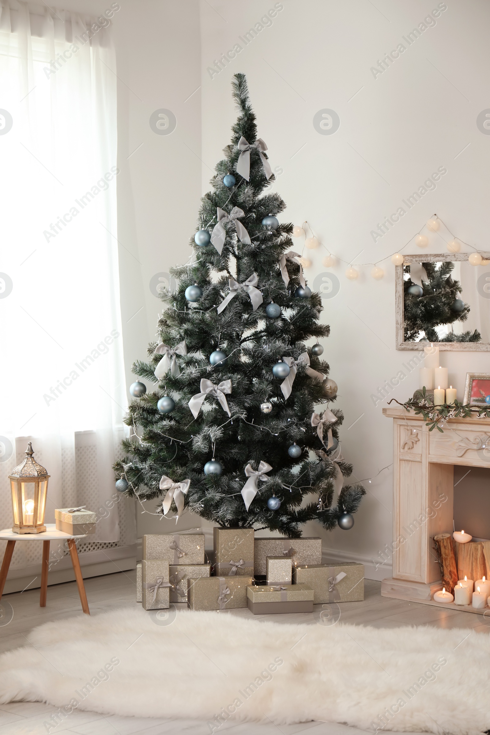 Photo of Decorated Christmas tree with gift boxes and fireplace in stylish living room interior
