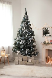 Decorated Christmas tree with gift boxes and fireplace in stylish living room interior