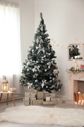 Photo of Decorated Christmas tree with gift boxes and fireplace in stylish living room interior