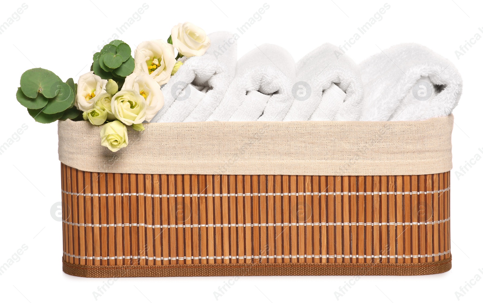 Photo of Wicker basket with folded soft terry towels, flowers and eucalyptus branch on white background