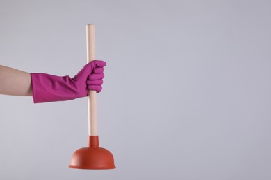 Photo of Woman holding plunger on light grey background, closeup. Space for text