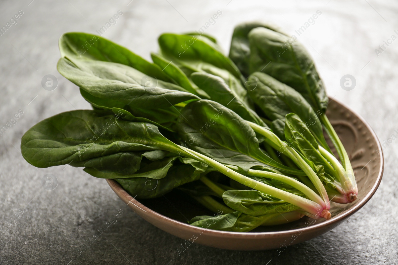 Photo of Fresh green healthy spinach leaves on grey table, closeup