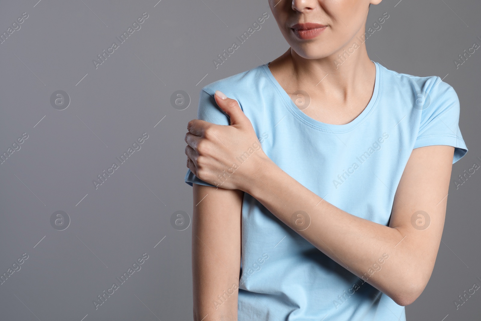 Photo of Woman suffering from shoulder pain on beige background, closeup. Space for text