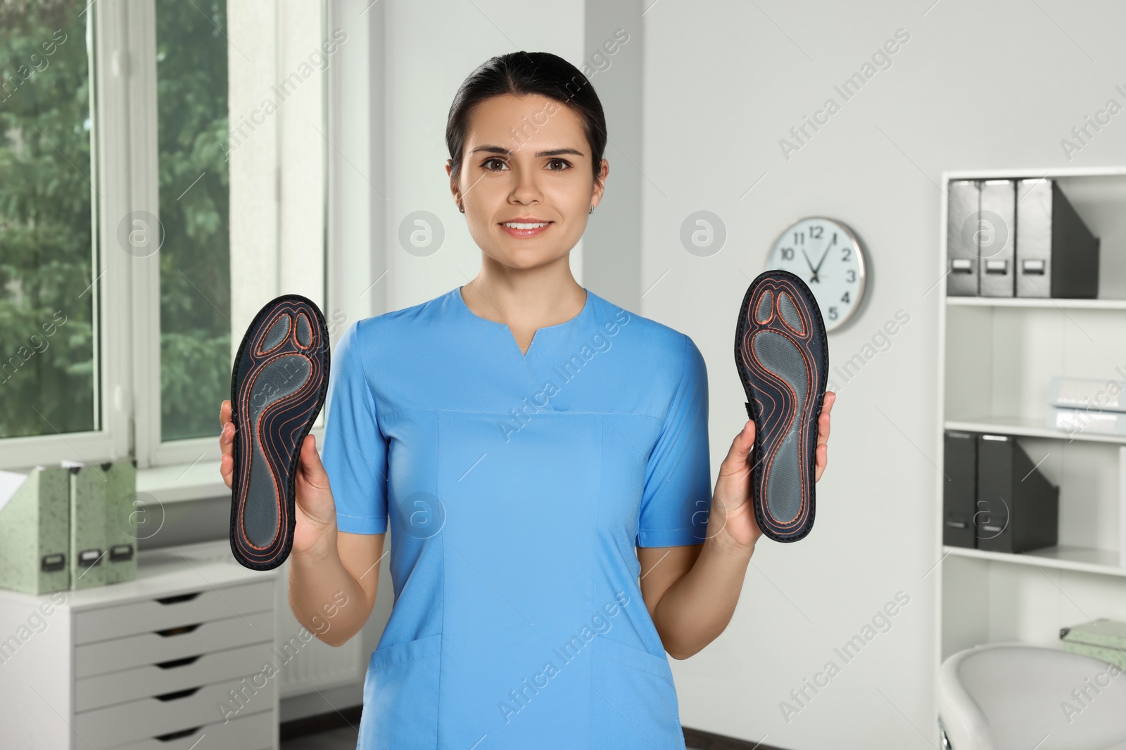 Photo of Beautiful female orthopedist showing insoles in hospital