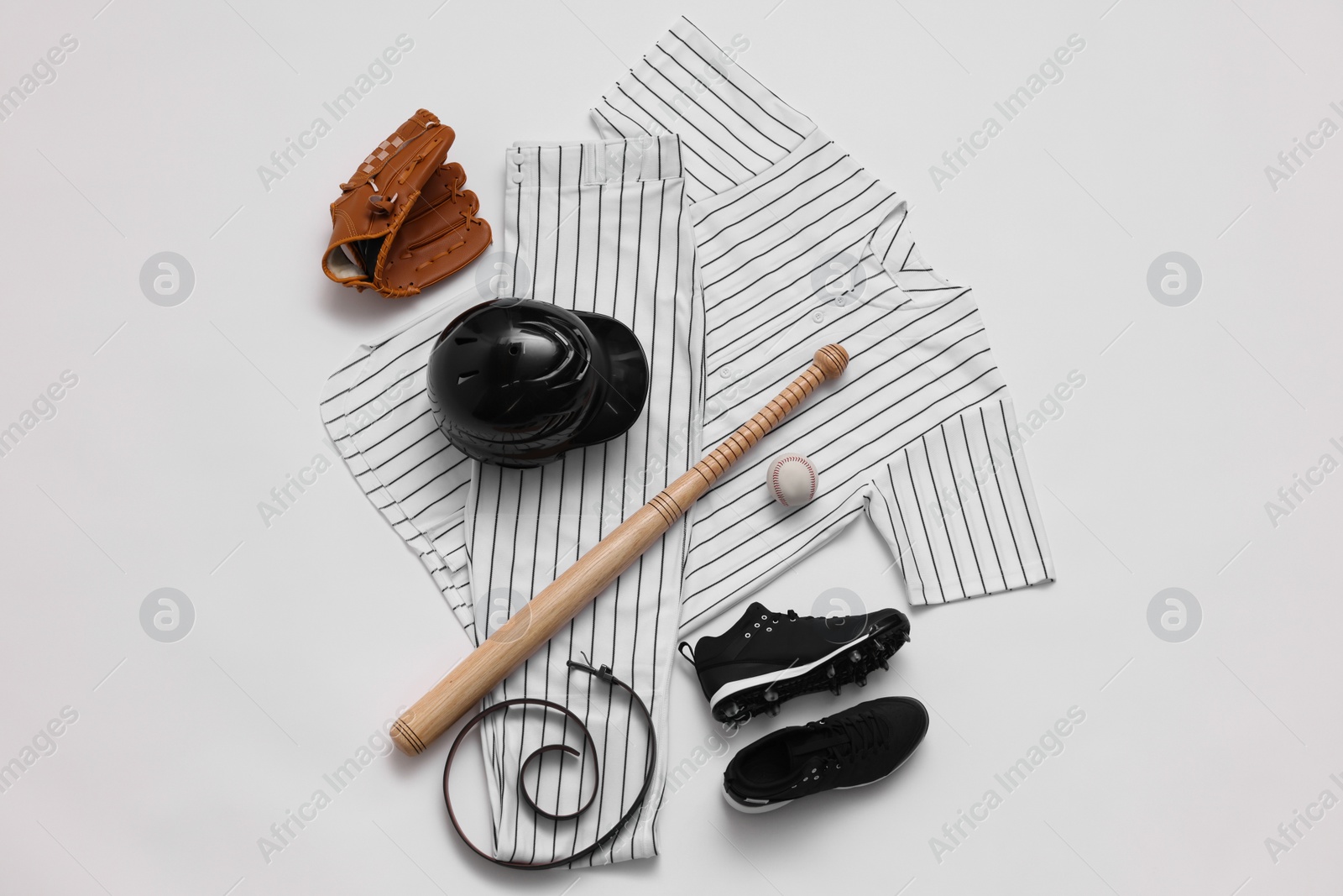 Photo of Baseball uniform and other sports equipment on white background, flat lay