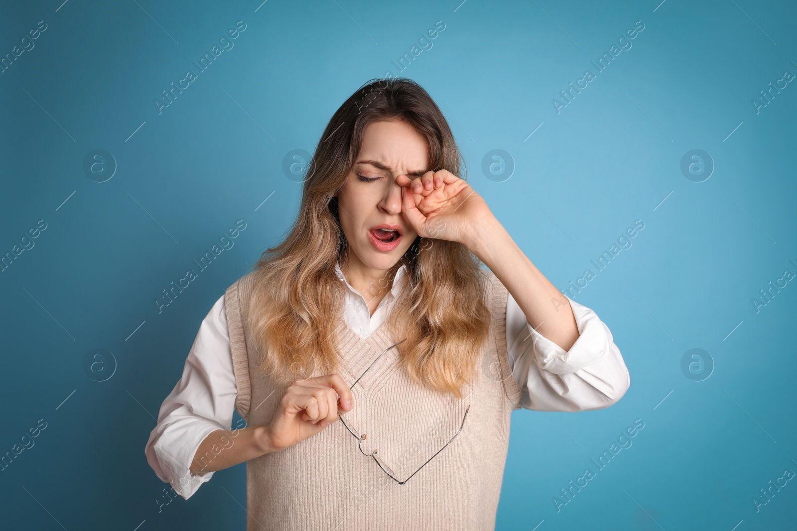 Photo of Young tired woman yawning on light blue background