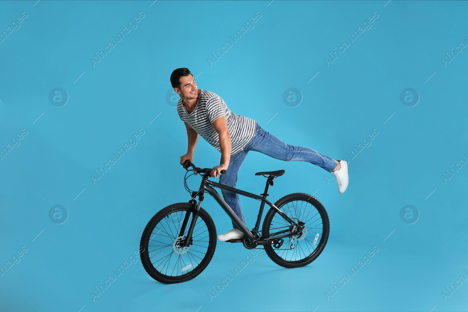 Photo of Handsome young man with modern bicycle on light blue background