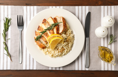 Delicious chicken risotto served on wooden table, flat lay