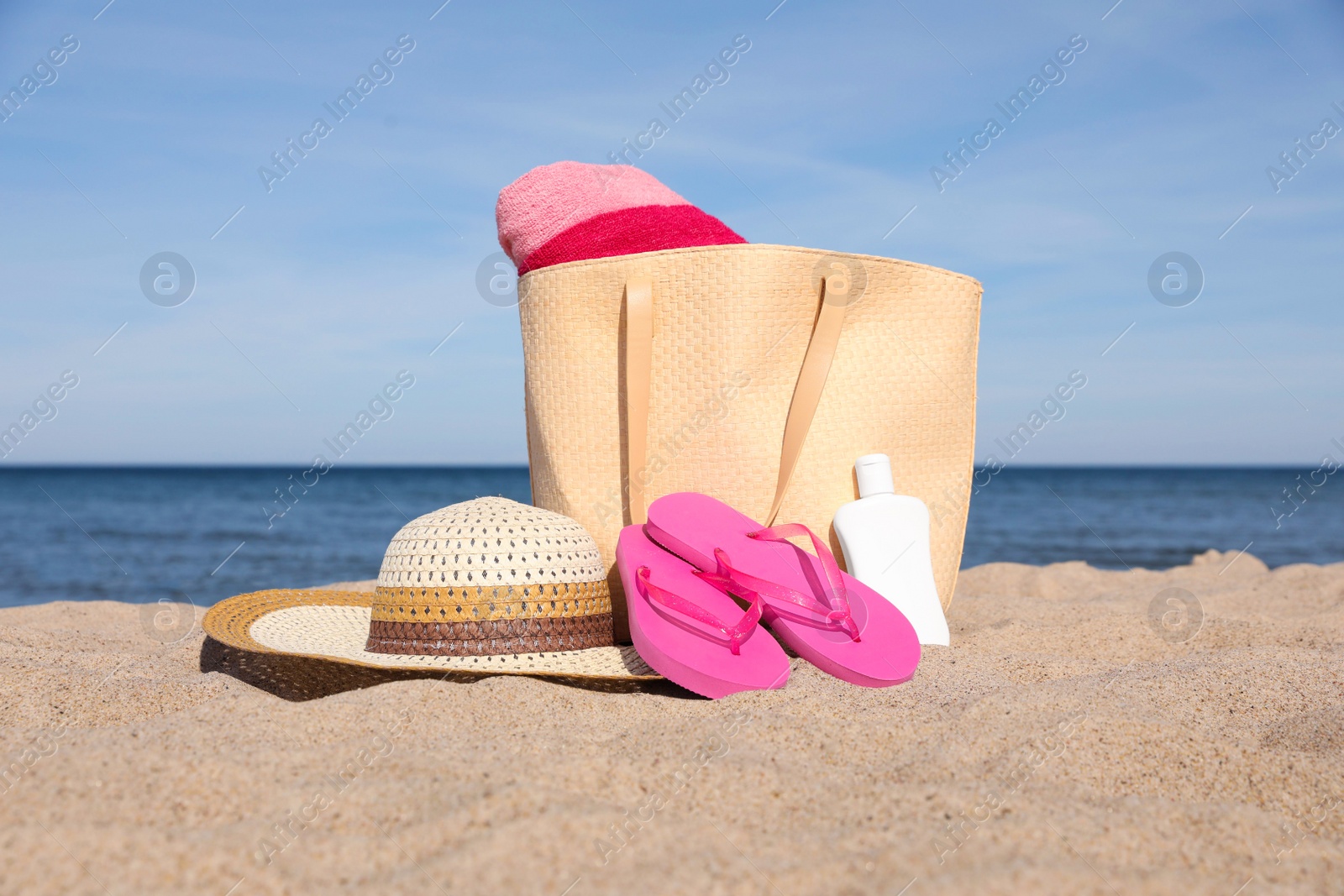 Photo of Summer bag with beach accessories on sand near sea