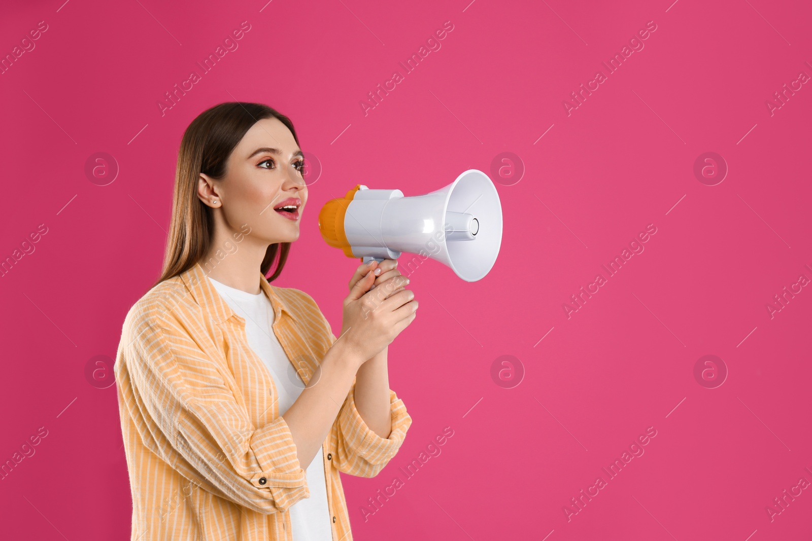 Photo of Young woman with megaphone on pink background. Space for text