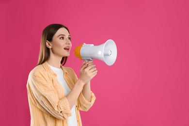 Young woman with megaphone on pink background. Space for text