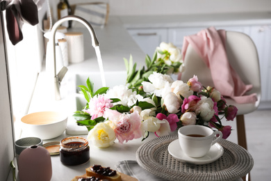 Beautiful peonies and cup of tea on kitchen counter