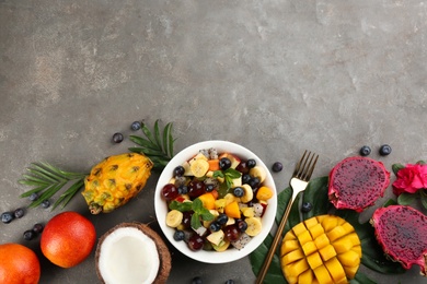 Flat lay composition with delicious exotic fruit salad on grey table. Space for text