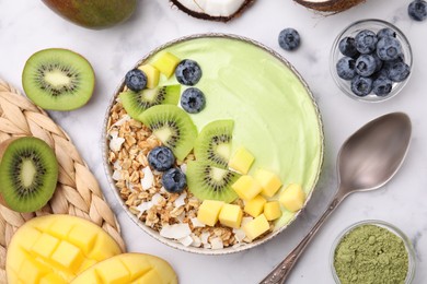Photo of Tasty matcha smoothie bowl with fresh fruits and oatmeal served on white marble table, flat lay. Healthy breakfast