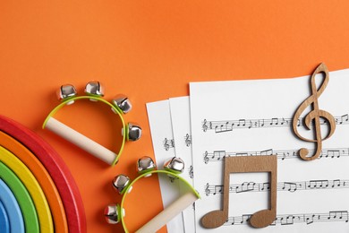 Photo of Tools for creating baby songs. Flat lay composition with tambourines for kids on orange background
