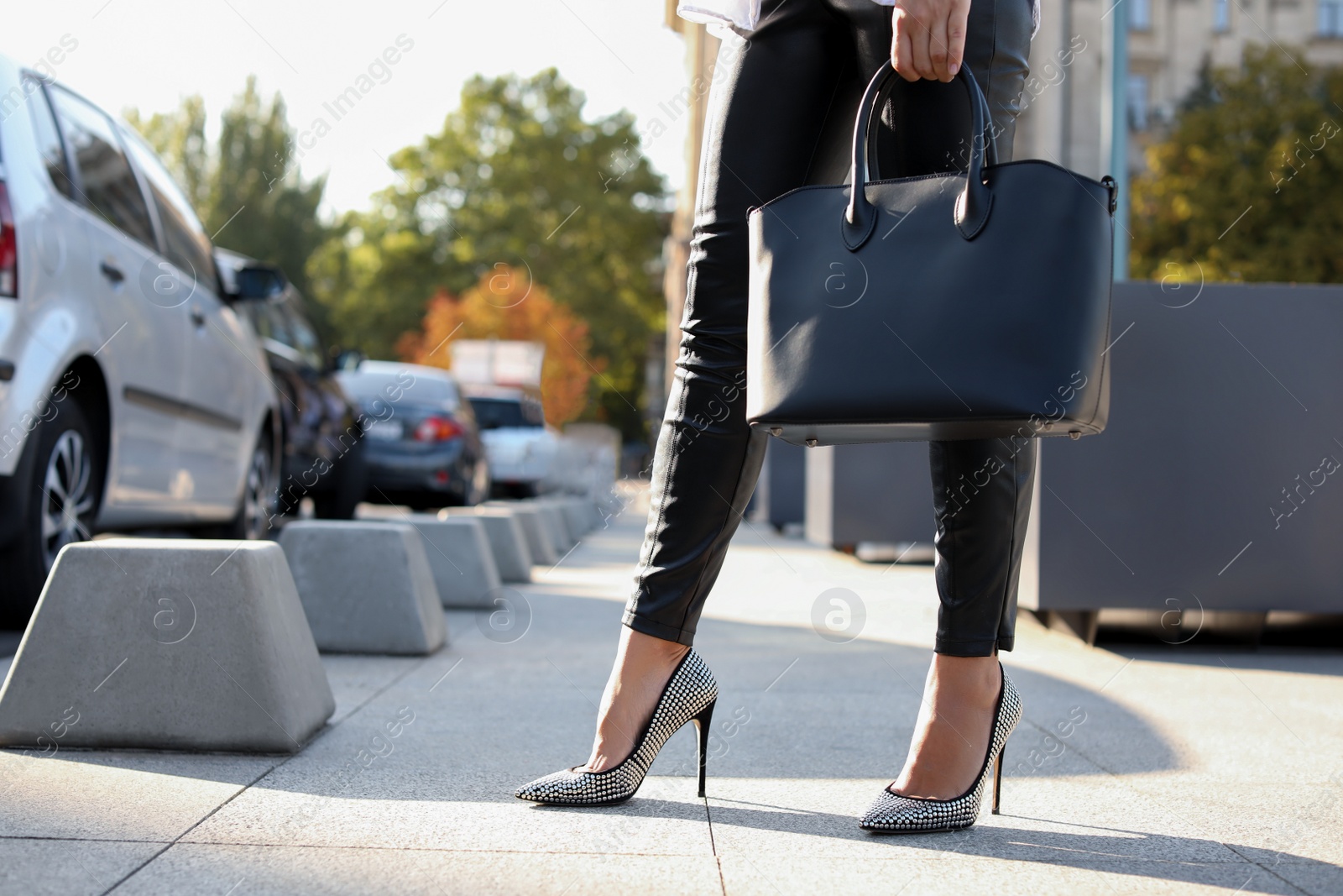 Photo of Young woman with stylish black bag on city street, closeup