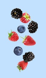 Image of Blackberries, blueberries, strawberries and raspberries falling on light blue background